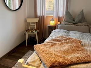 a bedroom with a bed and a chair and a mirror at Haus Swanhild in Fockbek