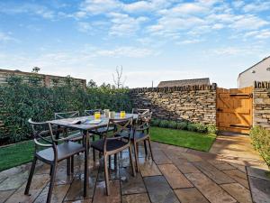 a table and chairs on a patio with a stone wall at 3 Bed in Loweswater 94152 in Arlecdon
