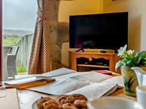 a table with a plate of food and a television at 3 Bed in Malham 94259 in Airton