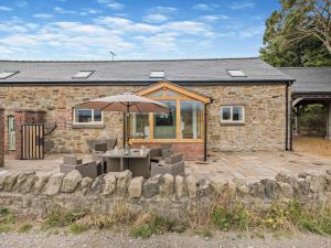 a stone house with a table and an umbrella at 4 Bed in Mold 92663 in Treuddyn