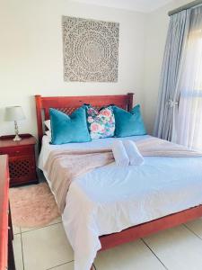 a bedroom with a large bed with blue pillows at The Blyde Crystal Lagoon Cologne4 in Pretoria