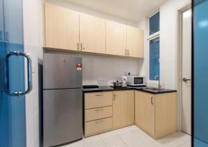 une cuisine avec des armoires en bois et un réfrigérateur en acier inoxydable dans l'établissement The Wave Heritage Residence Malacca-Near to Jonker Walk, à Malacca