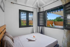 a small room with a bed and two windows at Villa NatHan in Les Trois-Îlets +22 photos