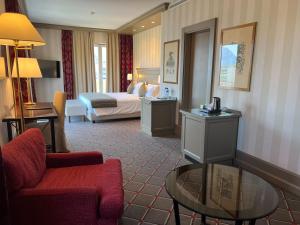 ein Hotelzimmer mit einem Bett, einem Sofa und einem Tisch in der Unterkunft Hotel De La Paix in Lugano
