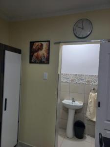 uma casa de banho com um lavatório e um relógio na parede em First Class Lodge em Benoni