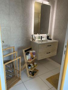 een badkamer met een wastafel en een spiegel bij Le Madras du Tombolo in Sainte-Marie