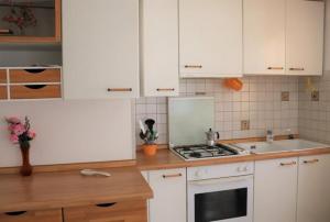 een keuken met witte kasten en een fornuis met oven bij Cozy charm near the beach - Beahost in Bibione