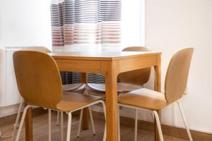 a wooden table with four chairs around it at Renovado apartamento a 10 min del Aeropuerto y a 3 min de IFEMA in Madrid