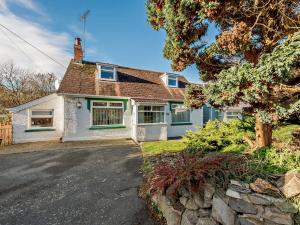 a white house with a tree and a driveway at 4 Bed in Aberporth 93783 in Aberporth