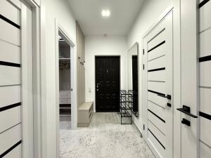 a hallway with white walls and a black door at Arcadia Luxury Apartments in Odesa