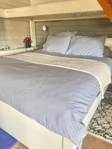 a bed with a white and blue striped blanket at La Dependance de la Villa des Oiseaux - La Petite Pierre in La Petite-Pierre