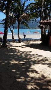 a person walking on a beach with palm trees at Calumar Guest House in Ubatuba