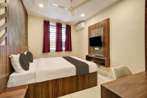 een slaapkamer met een bed en een televisie. bij GYPSY HOTEL CUSAT in Cochin