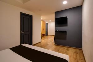 a bedroom with a bed and a television on a wall at Super Townhouse City Centre 2 Downtown - Managed by Company in Kolkata