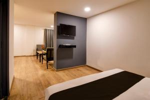 a room with a bed and a tv on a wall at Super Townhouse City Centre 2 Downtown - Managed by Company in Kolkata