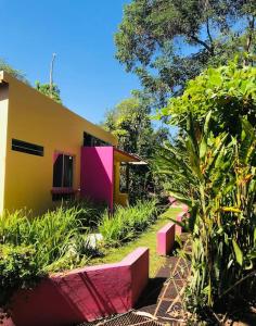 a house with pink and yellow in a garden at Casita Primavera / Casa Comalli in Comala