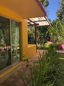a yellow house with a walkway in a garden at Casita Primavera / Casa Comalli in Comala