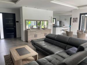 a living room with a black leather couch and a kitchen at Grande villa avec piscine et spa in Longages