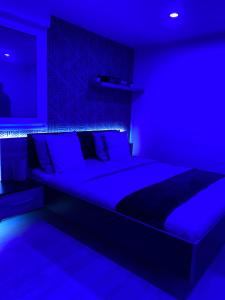 Atelier chaleureux 40m2 - Jacuzzi - proche CDG Parc des expo في ترمبلاي-ن-فرانس: غرفة نوم زرقاء مع سرير كبير مع إضاءة زرقاء