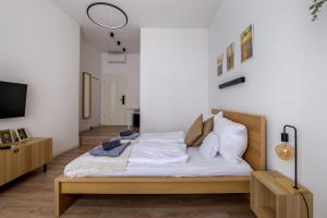 Schlafzimmer mit einem Bett mit weißer Bettwäsche und Kissen in der Unterkunft AK7 Boutique Suites in Budapest
