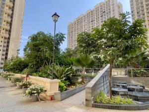 Prime 1 BHK in Hiranandani Powai في مومباي: حديقة بها مقاعد وأشجار ومباني