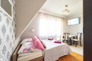 ein Schlafzimmer mit einem Bett mit rosa Kissen in der Unterkunft Apartamenty nad Młynówką in Chochołów
