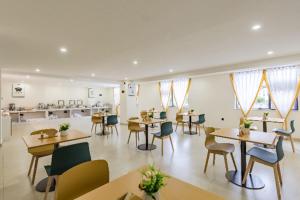 a dining room with tables and chairs and windows at City Comfort Inn Kunming Dashuying Yejin Hospital Wangdaqiao in Kunming