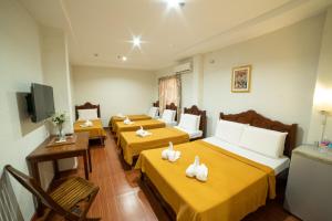 Cette chambre comprend 4 lits et une télévision. dans l'établissement Casañas Suites, à Puerto Princesa