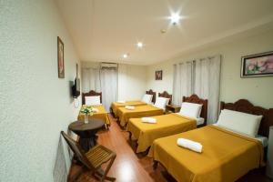 a room with four beds with yellow sheets at Casañas Suites in Puerto Princesa City