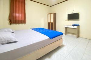 a bedroom with a bed and a tv on the wall at Wisma Sodikin Mitra RedDoorz in Palembang