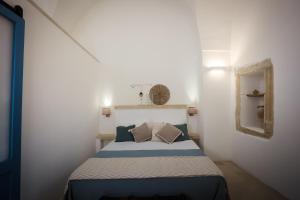 um pequeno quarto com uma cama num quarto branco em Skafè Apartments em Uggiano la Chiesa