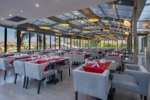 um restaurante com mesas e cadeiras com guardanapos vermelhos em Sisus Marina Hotel em Cesme