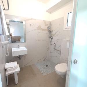 a white bathroom with a sink and a toilet at Lido Di Alghero Rooms on the Beach in Alghero