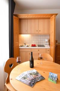 eine Küche mit einem Holztisch mit zwei Gläsern Wein in der Unterkunft Eden Apartments in Seis am Schlern