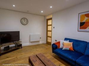 a living room with a blue couch and a tv at Central seaside home with peaceful patio in Brighton & Hove