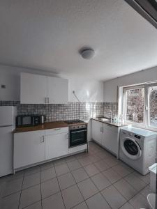uma cozinha com armários brancos e uma máquina de lavar e secar roupa em Pinova em Karlsruhe