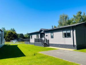 a house with a green lawn in front of it at The Waterhole Lodge with Hot Tub in Barmby on the Moor