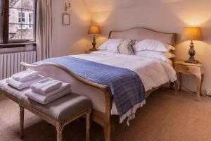 a bedroom with a large bed with a bench and two lamps at Sign of the Angel in Lacock
