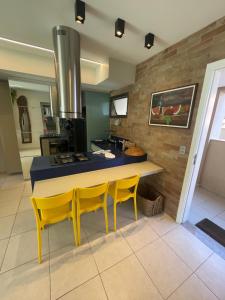 a kitchen with yellow chairs and a table and a stove at EKOARA BEIRA MAR 127 in Porto De Galinhas