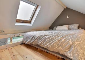 een slaapkamer met een bed op een zolder met een raam bij Chambre d hôtes - studio de 30m2 in Rixensart