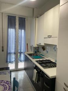a kitchen with white cabinets and a stove top oven at Appartamento con Balcone in Muggiò