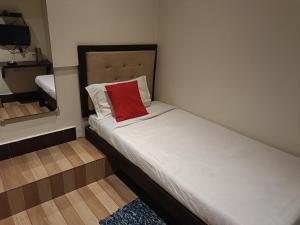 HOTEL SERENE في شيلونغ: سرير صغير ومخدة حمراء في الغرفة