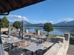 a patio with tables and chairs and a view of a lake at Seehotel Hartung & Ferienappartements in Füssen
