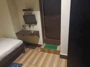 HOTEL SERENE في شيلونغ: غرفة نوم صغيرة بها سرير وتلفزيون