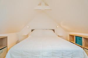 ein großes weißes Bett in einem Zimmer mit Schränken in der Unterkunft Petit gîte Sables d' Or 600m plage in Plurien