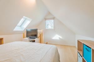 Schlafzimmer mit einem Bett, einem TV und einem Fenster in der Unterkunft Petit gîte Sables d' Or 600m plage in Plurien