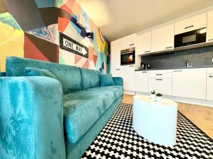 ein Wohnzimmer mit einem blauen Sofa und einer Küche in der Unterkunft Kreative Wohnung mit Balkon in Wien