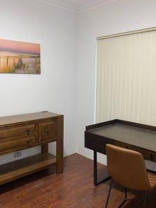 un escritorio y una silla en una habitación con una pintura en Falcon Estuary Escape en Wannanup