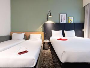 two beds in a hotel room with red shoes on them at ibis Paris Grands Boulevards Opéra 9e in Paris