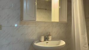 Baño blanco con lavabo y espejo en Jason's House, en Corfú